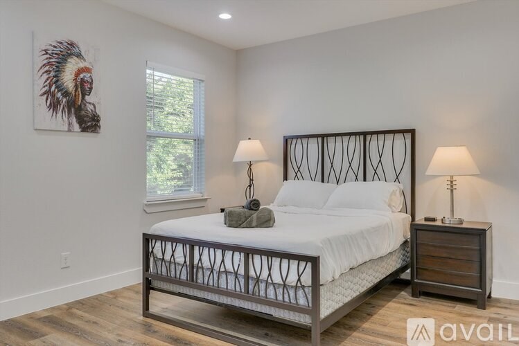 A bedroom with a large bed, a nightstand, and a painting on the wall.