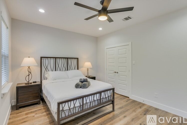 A bedroom with a bed, two lamps, and a ceiling fan.