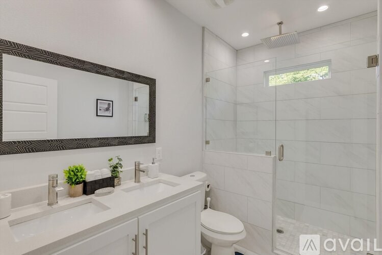 A bathroom with a white toilet, a sink with a mirror above it, and a glass shower stall.