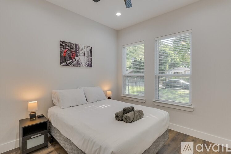 A bedroom with a bed, two lamps, and a picture on the wall.