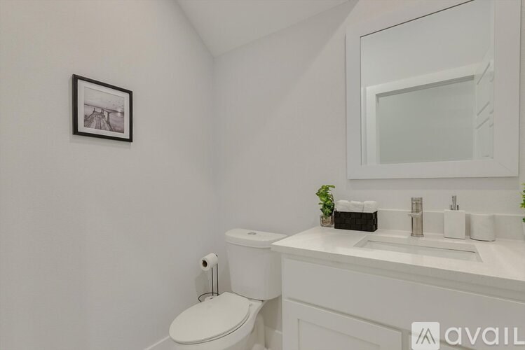 A white bathroom with a toilet, sink, and mirror.