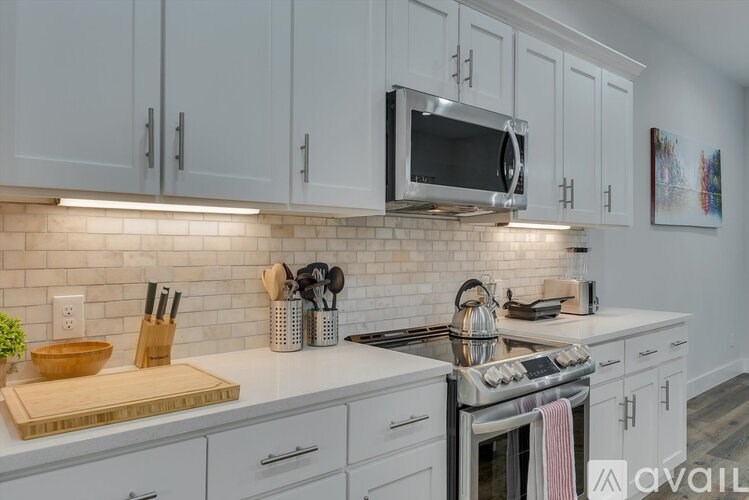 A kitchen with white cabinets and a stove top oven.