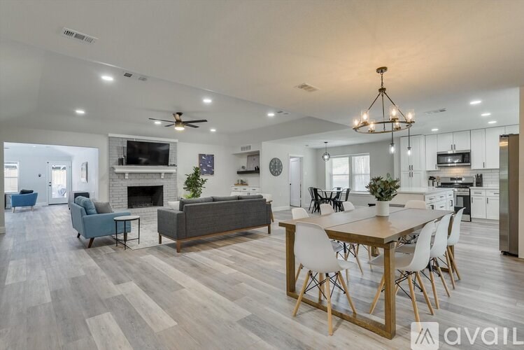 A modern living room with a grey couch, a wooden dining table, and a fireplace.