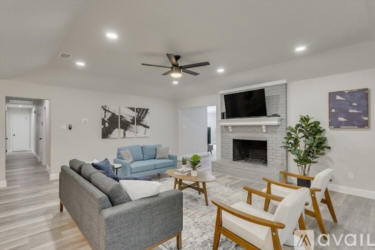 A living room with a grey couch, a white chair, a fireplace, and a ceiling fan.