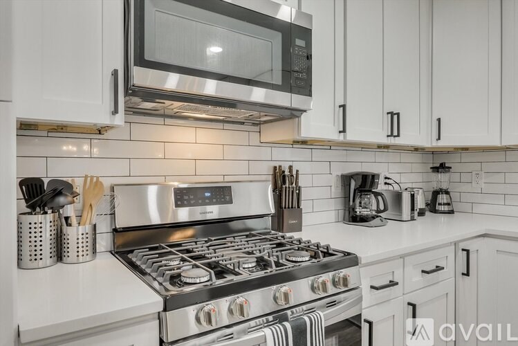 A modern kitchen with a stainless steel stove and white cabinets.