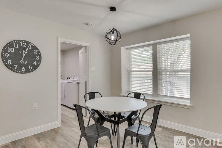 A dining room with a table, chairs, and a clock on the wall.