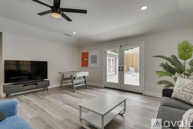 A living room with a television, a sofa, a coffee table, and a plant.