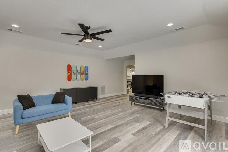 A living room with a blue couch, a white coffee table, a TV, and a shelf with various objects on it.