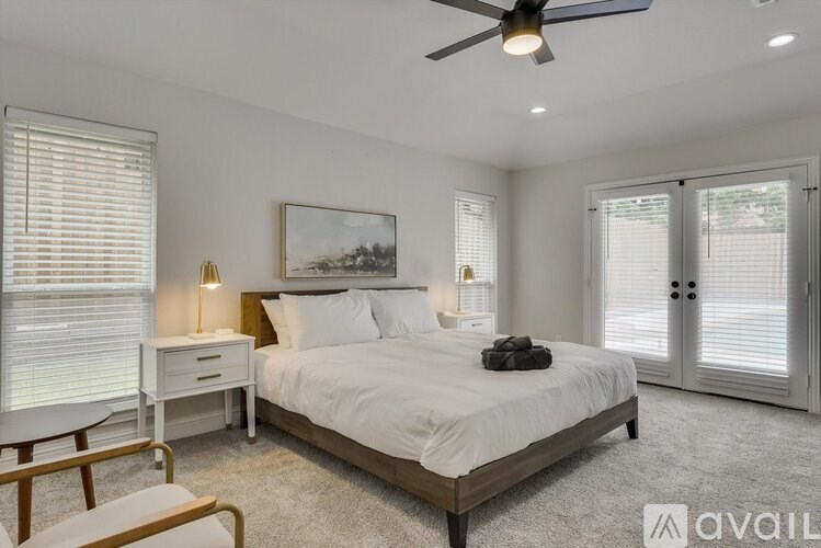 A bedroom with a bed, a chair, and a ceiling fan.