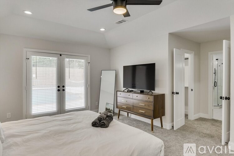 A bedroom with a bed, dresser, and television.