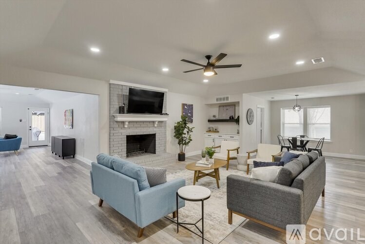 A living room with a grey couch, a blue couch, a fireplace, and a television.