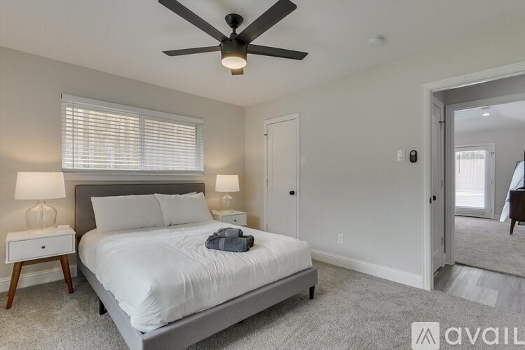 A bedroom with a bed, a ceiling fan, and two lamps.
