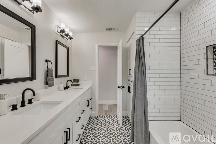 A bathroom with a white sink and black and white tiles.
