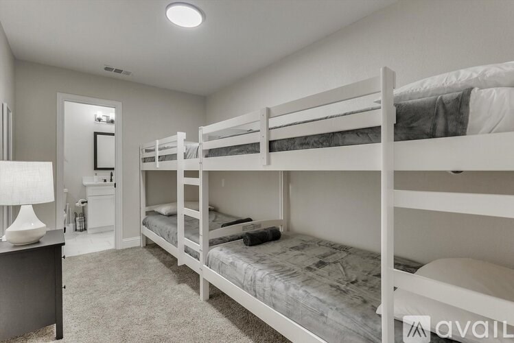 A bedroom with white bunk beds and a grey carpet.