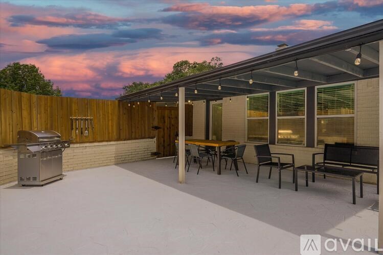 A patio with a table, chairs, and a grill.