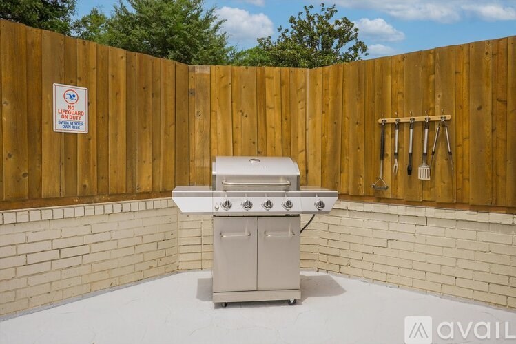 A BBQ grill is set up in a backyard with a wooden fence and a sign on the wall.