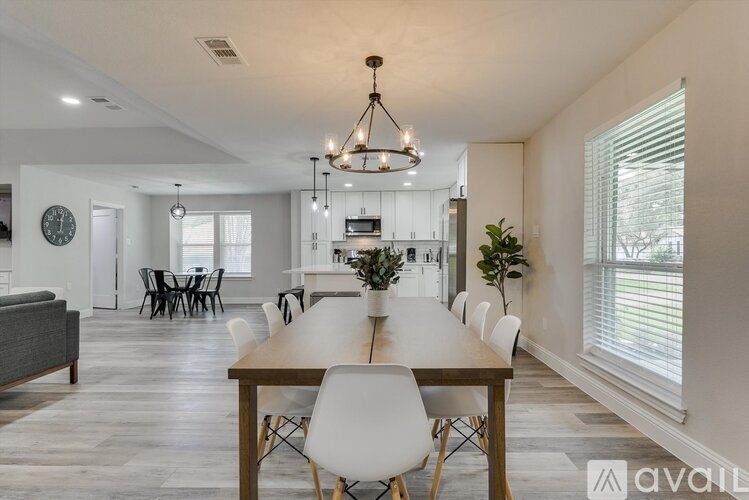 A modern dining room with a wooden table and white chairs.
