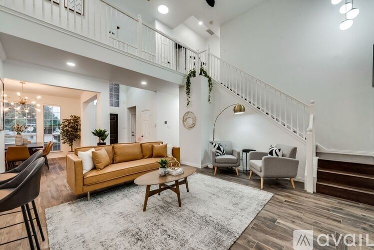 A living room with a couch, chairs, and a staircase.