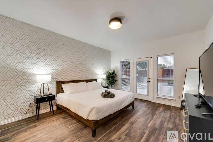A bedroom with a bed, nightstand, and a wall with a geometric pattern.