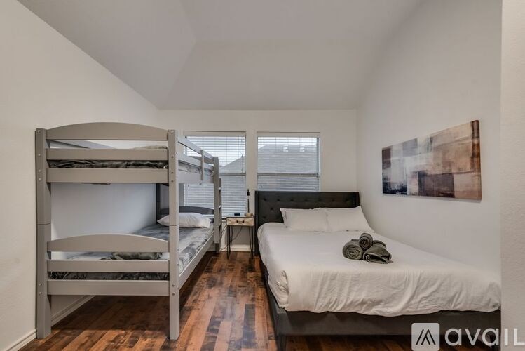 A room with a bunk bed and a single bed with a pillow and a towel on it.