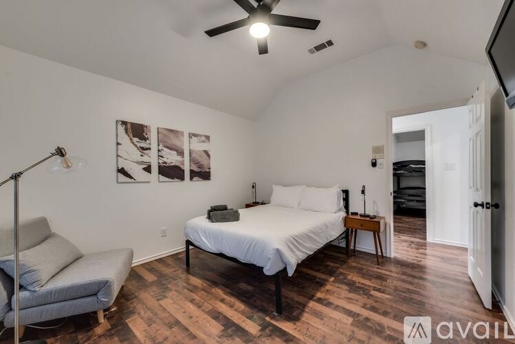 A bedroom with a bed, chair, and pictures on the wall.