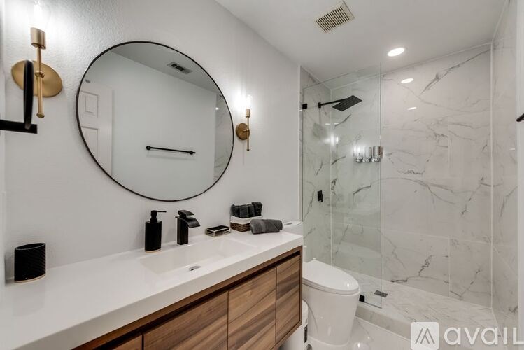 A bathroom with a marble wall and a round mirror above a sink.