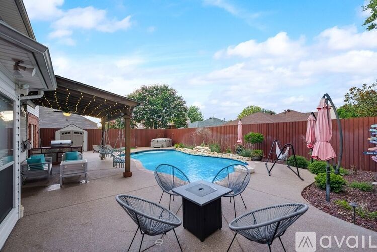 A backyard with a pool and patio furniture.
