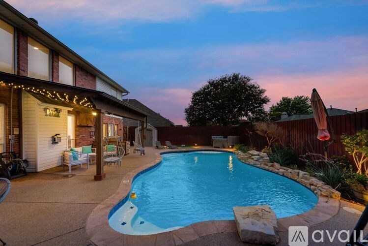 A backyard with a pool and a house with lights on.