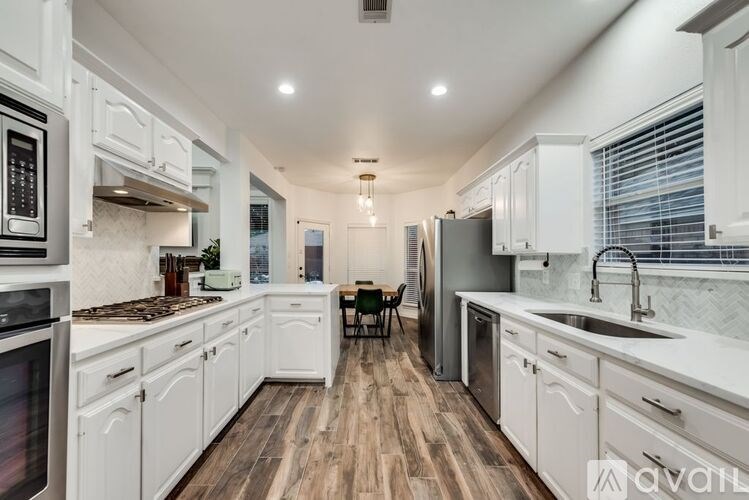 A kitchen with white cabinets and a wooden floor.