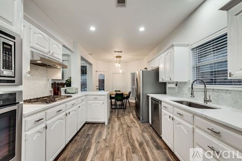 A kitchen with white cabinets and a wooden floor.