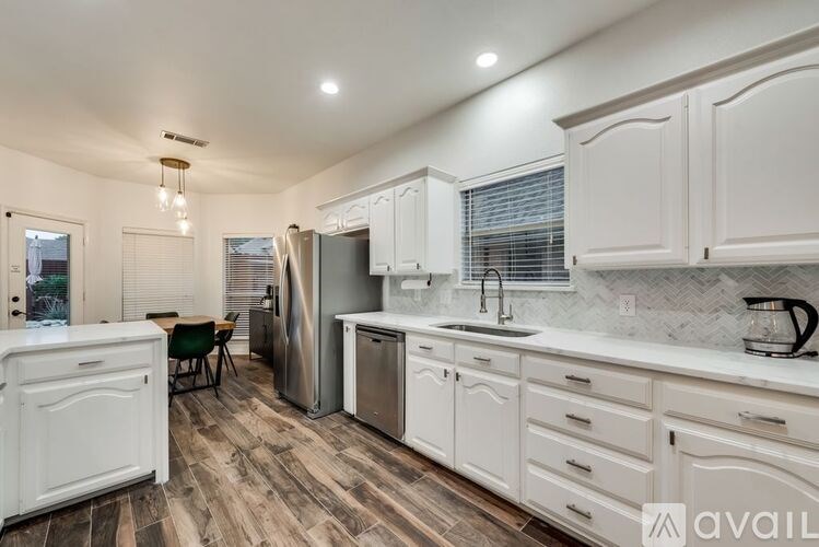 A kitchen with white cabinets and a wooden floor.
