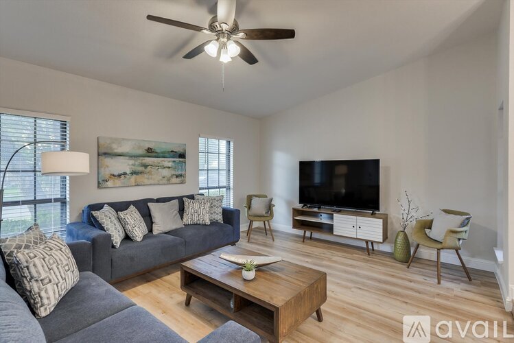 A living room with a grey couch, a wooden coffee table, a television, and a painting on the wall.