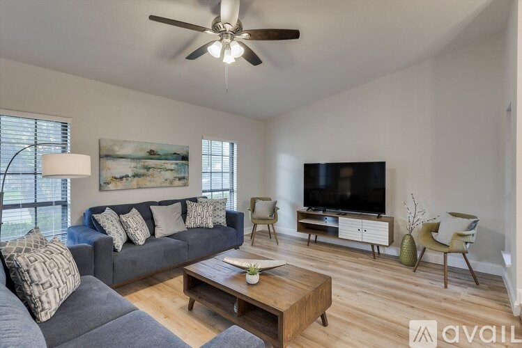 A living room with a grey couch, a wooden coffee table, a television, and a painting on the wall.
