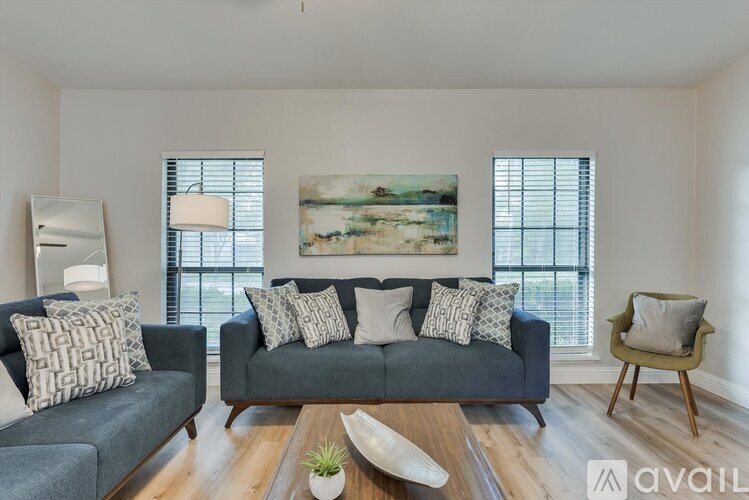 A living room with a grey couch, a wooden coffee table, and a painting on the wall.