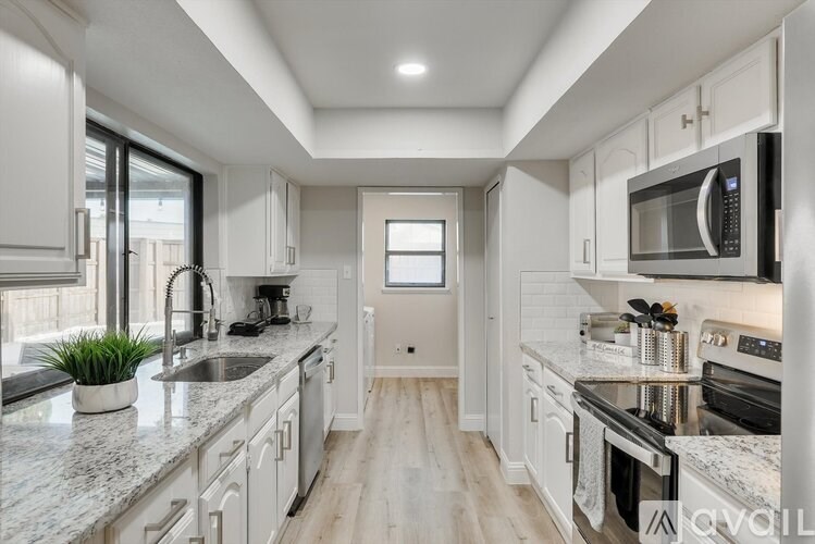 A modern kitchen with white cabinets and stainless steel appliances.
