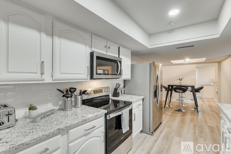 A modern kitchen with white cabinets and a black stove top oven.