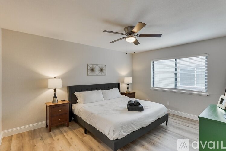 A bedroom with a bed, two lamps, and a ceiling fan.
