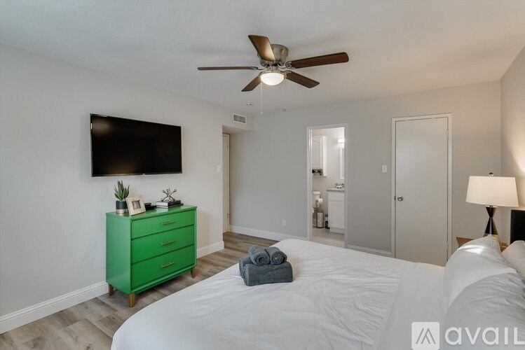 A bedroom with a green dresser and a flat screen TV mounted on the wall.