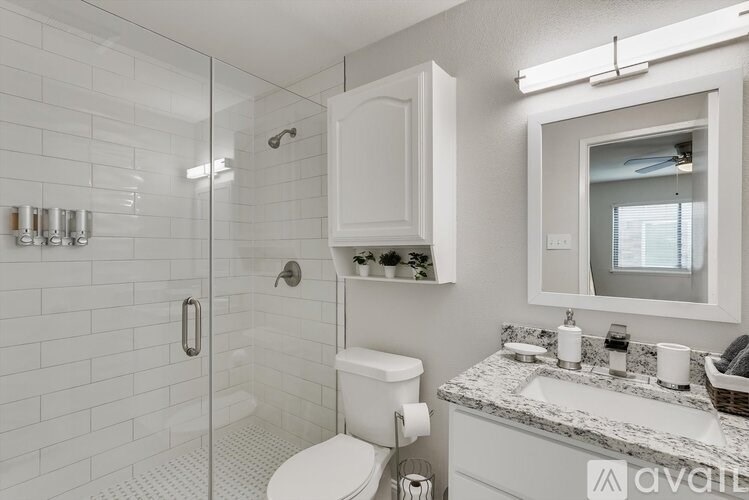 A white bathroom with a toilet, sink, and shower.