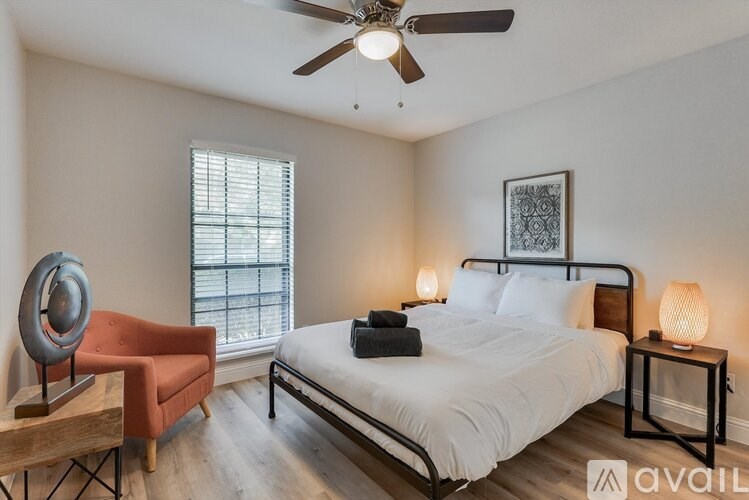 A bedroom with a bed, chair, and lamp.