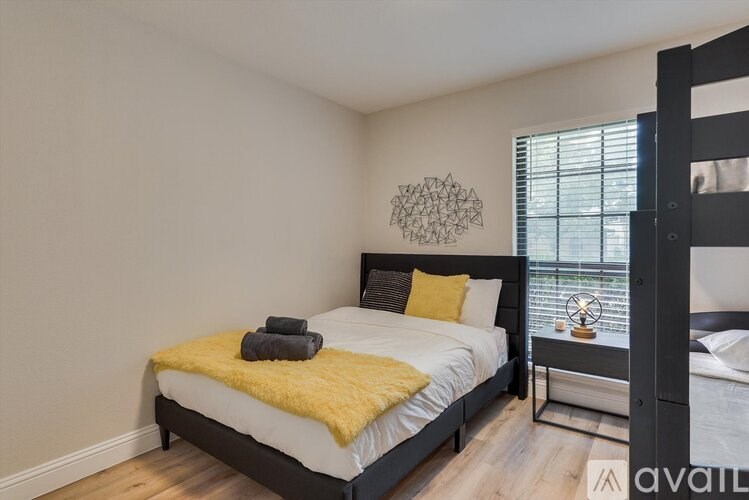 A bedroom with a bed, a nightstand, and a window.