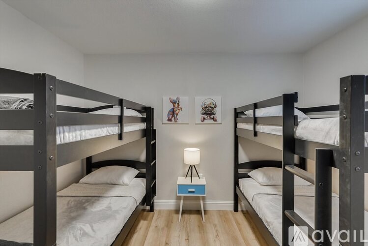 A room with two bunk beds and a small table with a lamp on it.