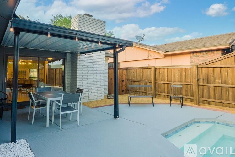 A patio with a table and chairs under a roof.