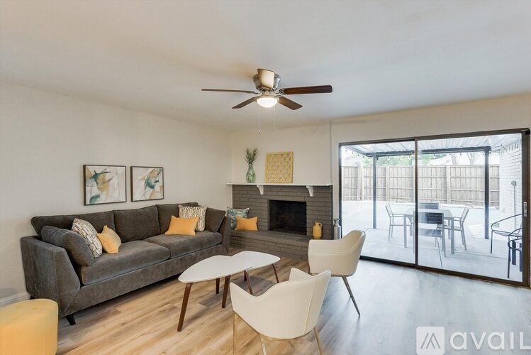 A living room with a grey couch, a fireplace, and a ceiling fan.