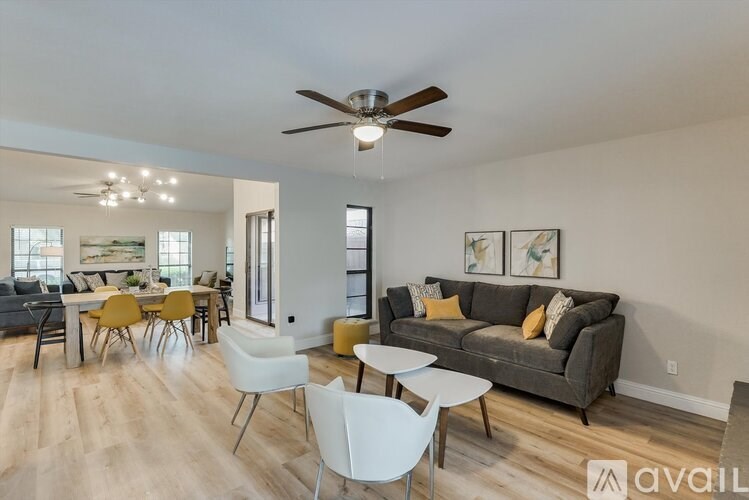 A living room with a grey couch and white chairs.