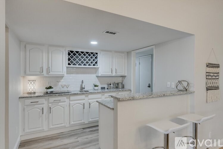 A kitchen with white cabinets and a marble countertop.