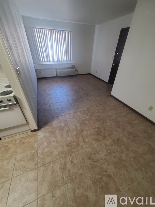 A room with tiled flooring and a window with blinds.