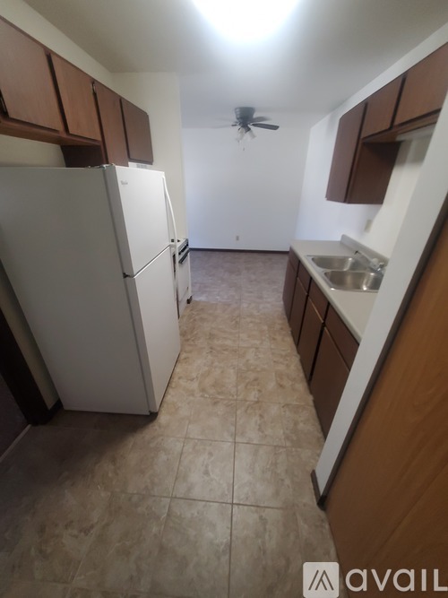 A kitchen with a white refrigerator and brown cabinets.