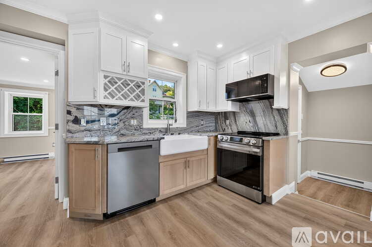 A kitchen with white appliances and cabinets, a sink, and a window.
