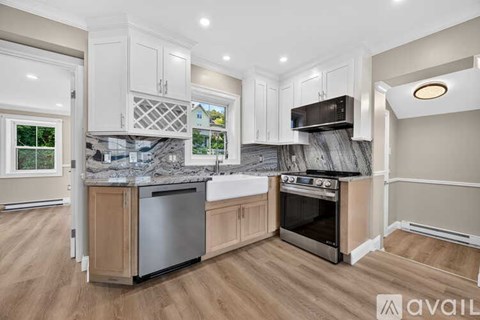 A kitchen with white appliances and cabinets, a sink, and a window.